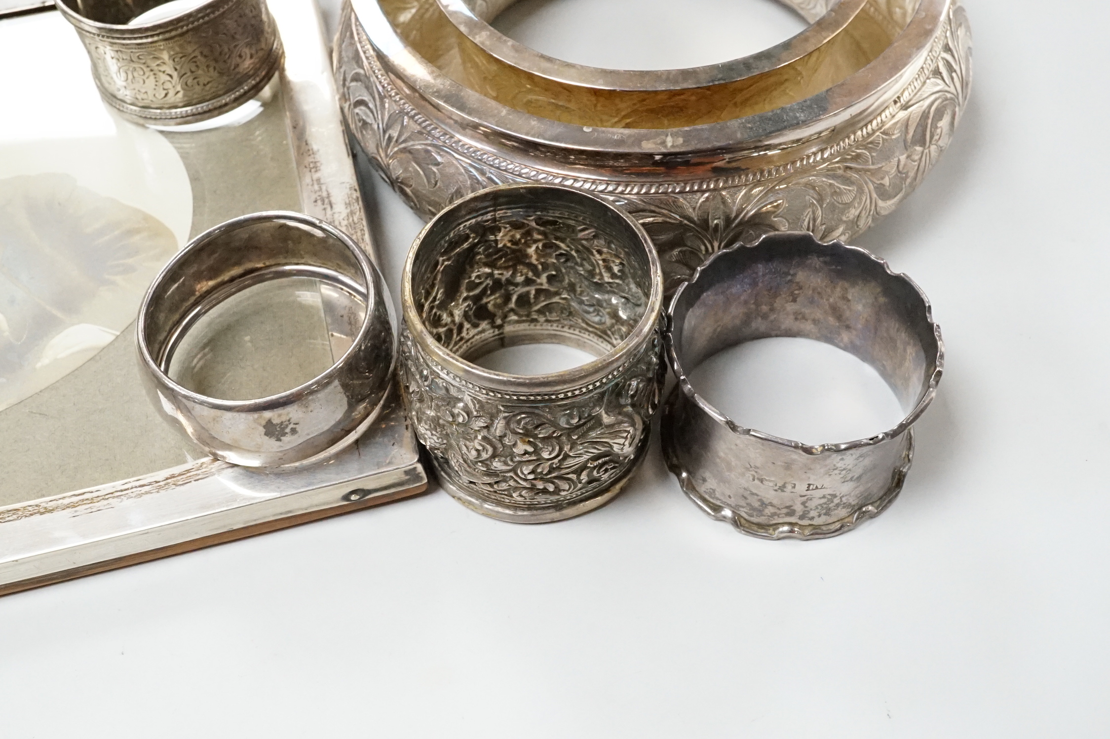 Two George V silver mounted photograph frames including oval, an Indian white metal flower holder and other items including silver napkin rings and a matchbox sleeve.